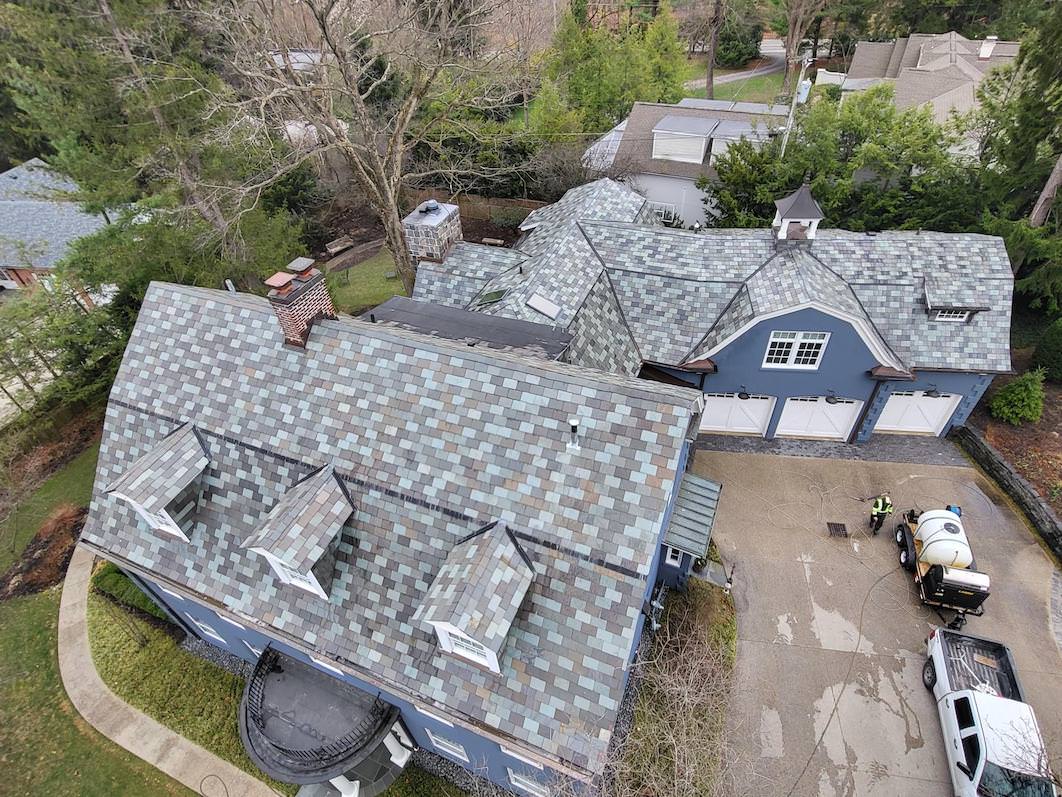 finished roof cleaning by forte surfaces on a blue house with multicolored roofing