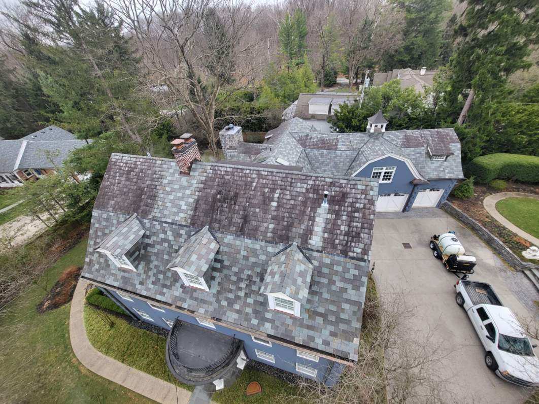before roof cleaning by forte surfaces on a blue house with multicolored roofing