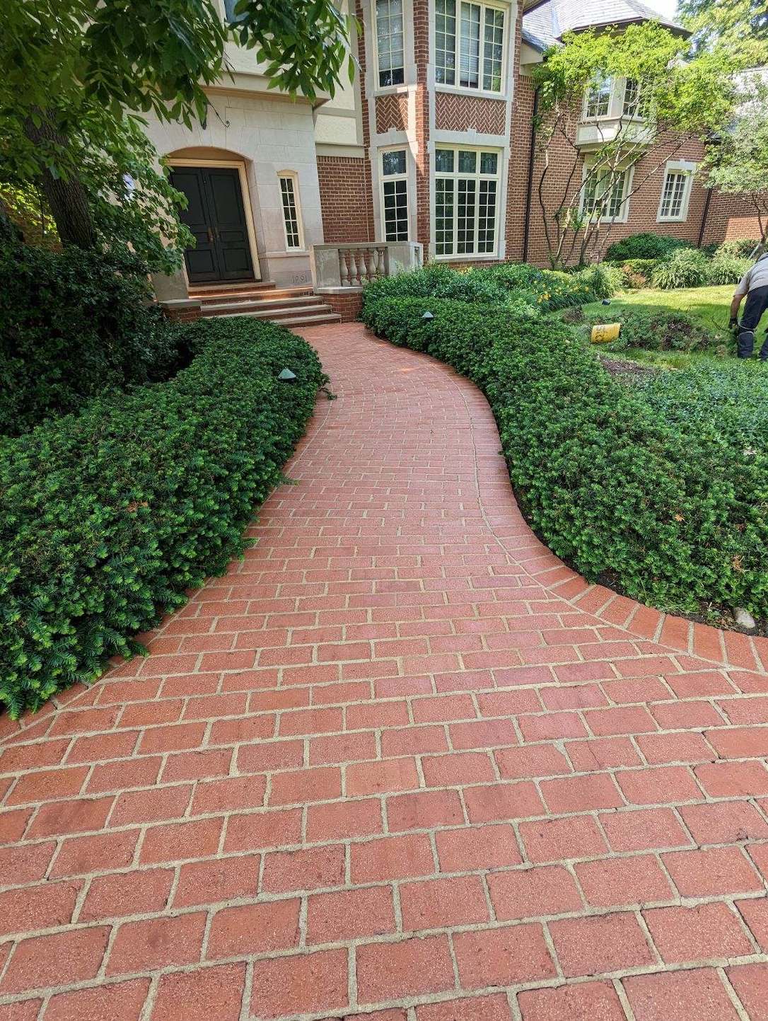 a freshly cleaned brick walkway leading to a large brick house