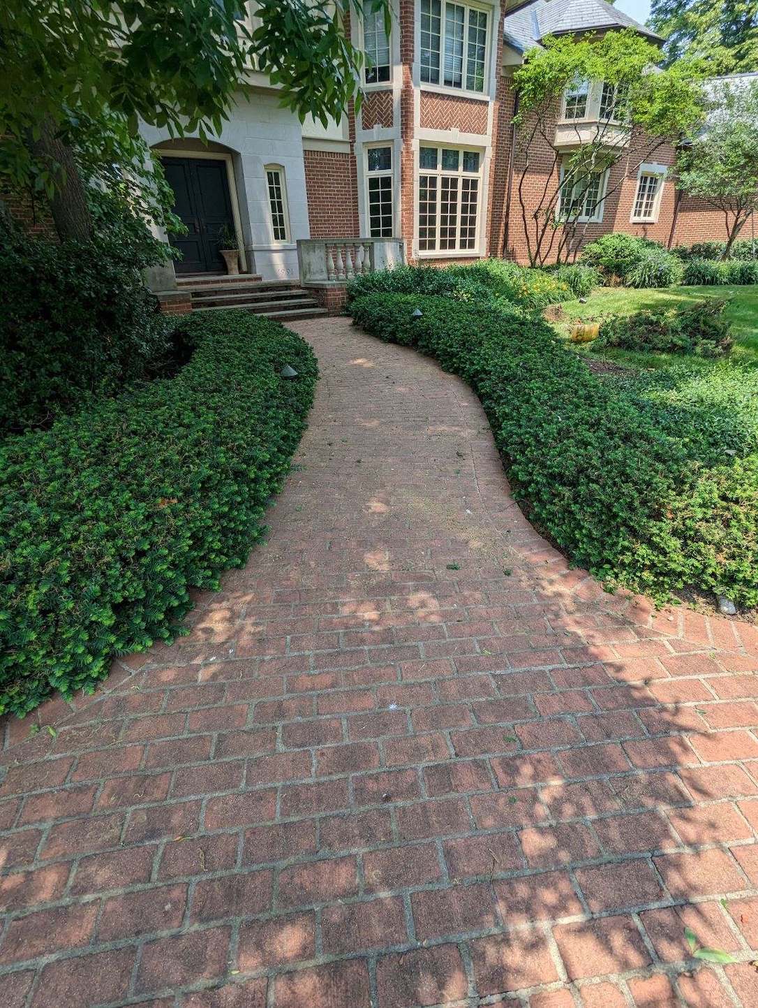 a brick walkway leading to a large brick house