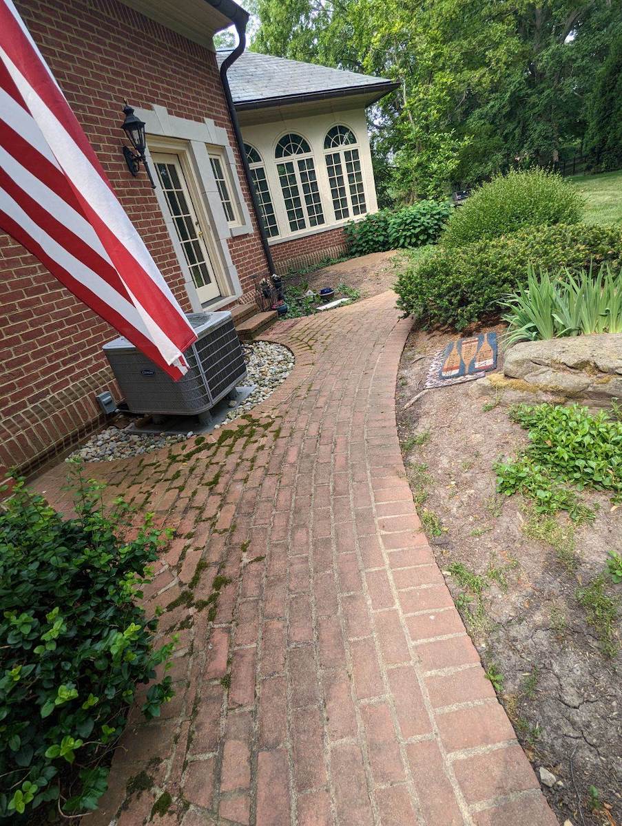 a brick walkway leading to a brick house with a flag on the side in need or a cleaning