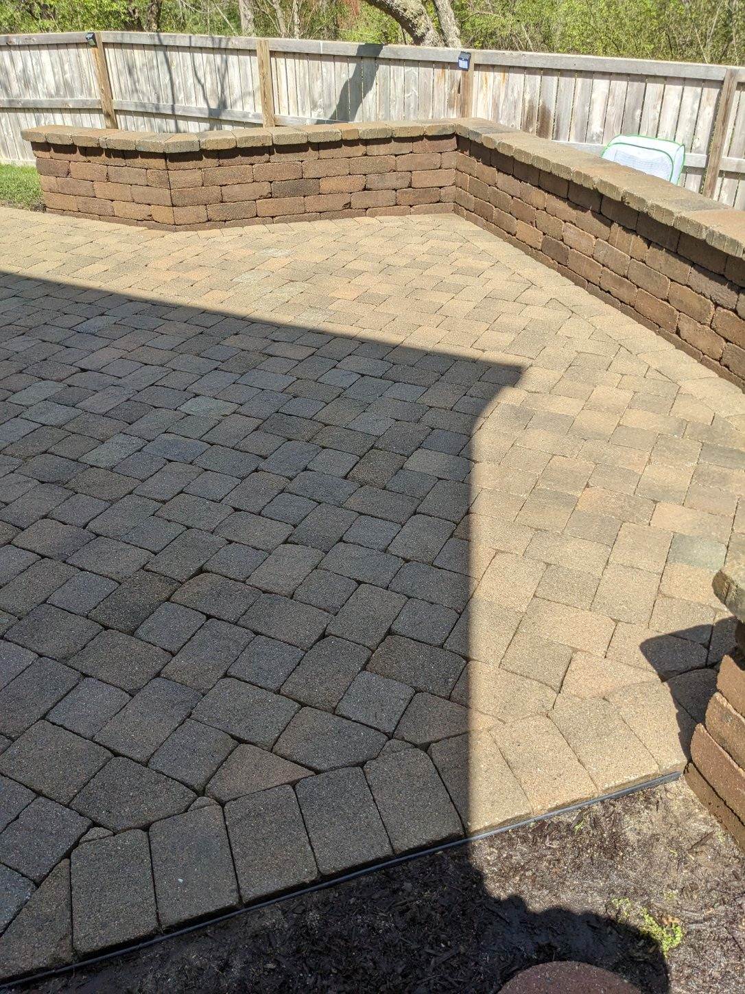 a brick patio with a wooden fence in the background