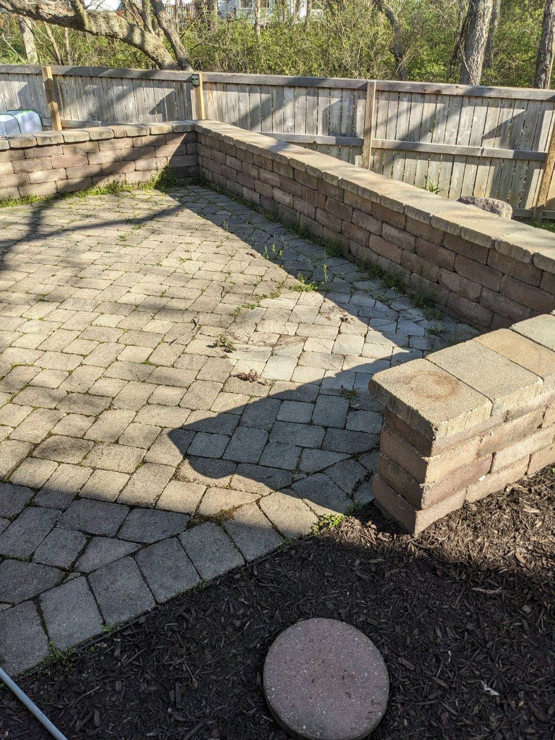 a brick patio with a wooden fence in the background
