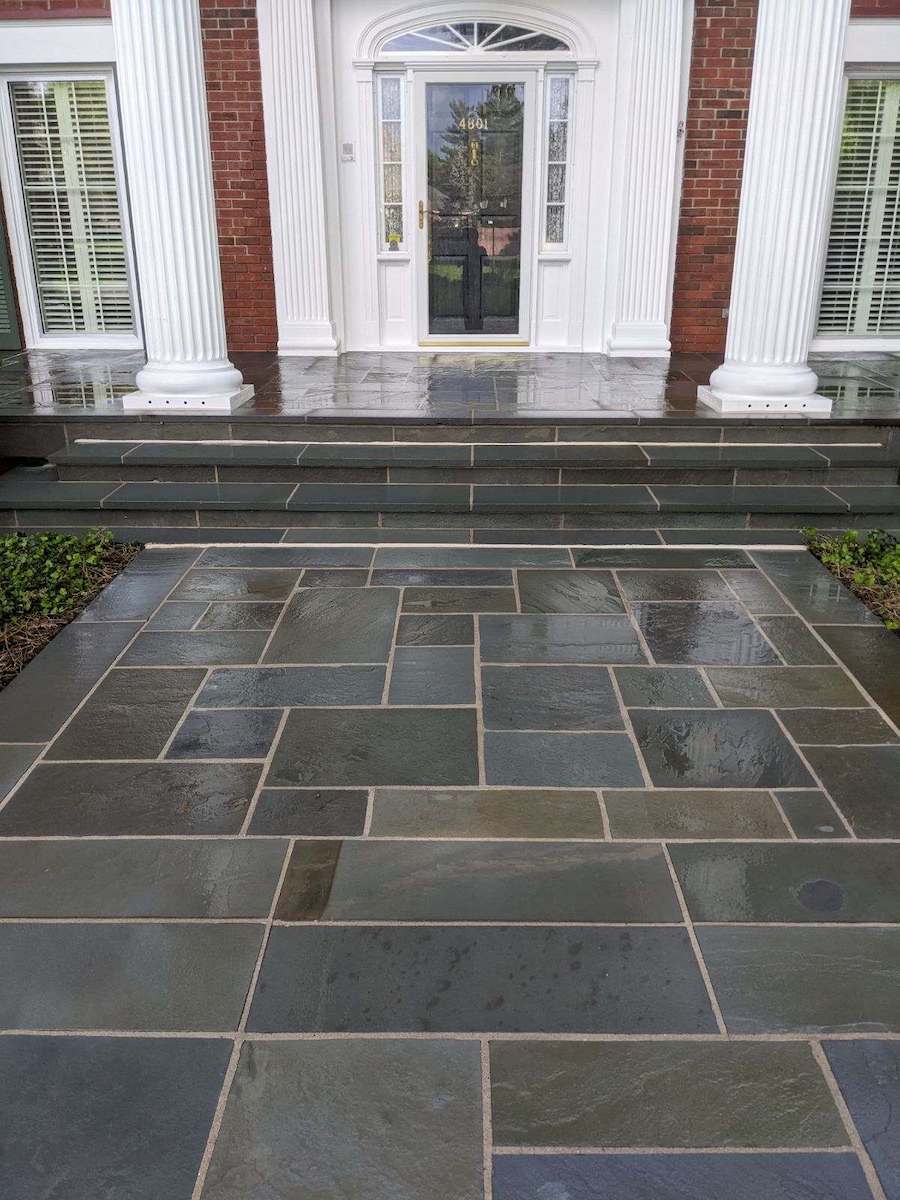 a stone walkway leads to the front door of a brick house
