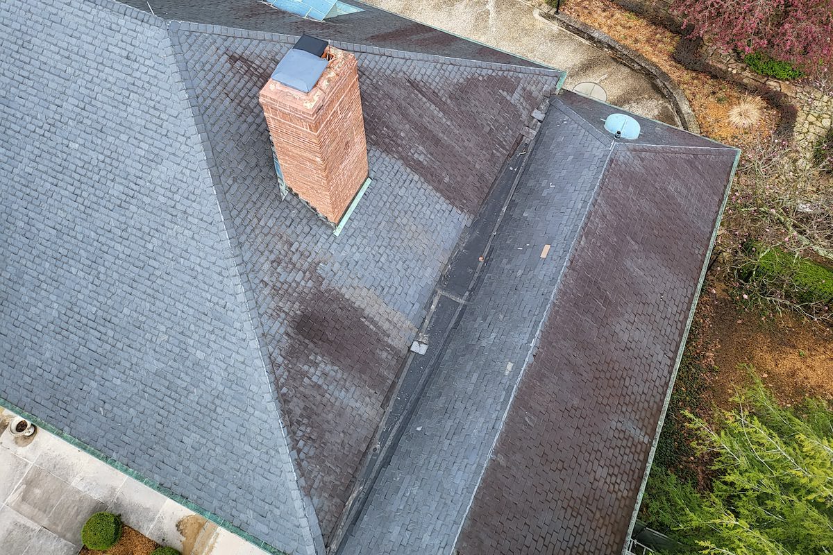 an aerial view of a roof that needs cleaned with a chimney on it
